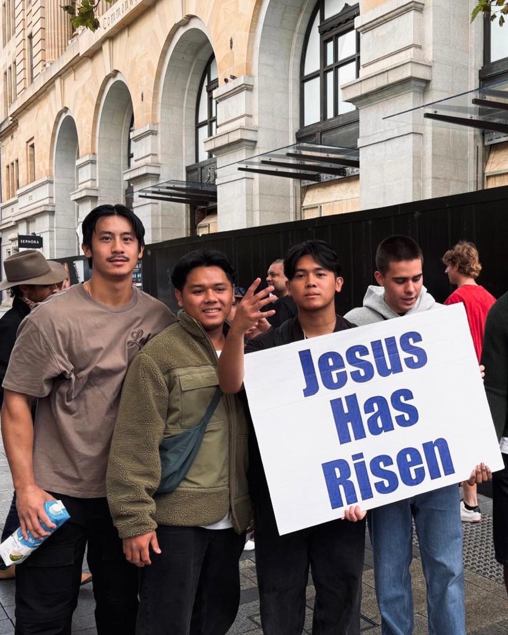 Young men holding a 'Jesus has risen' sign