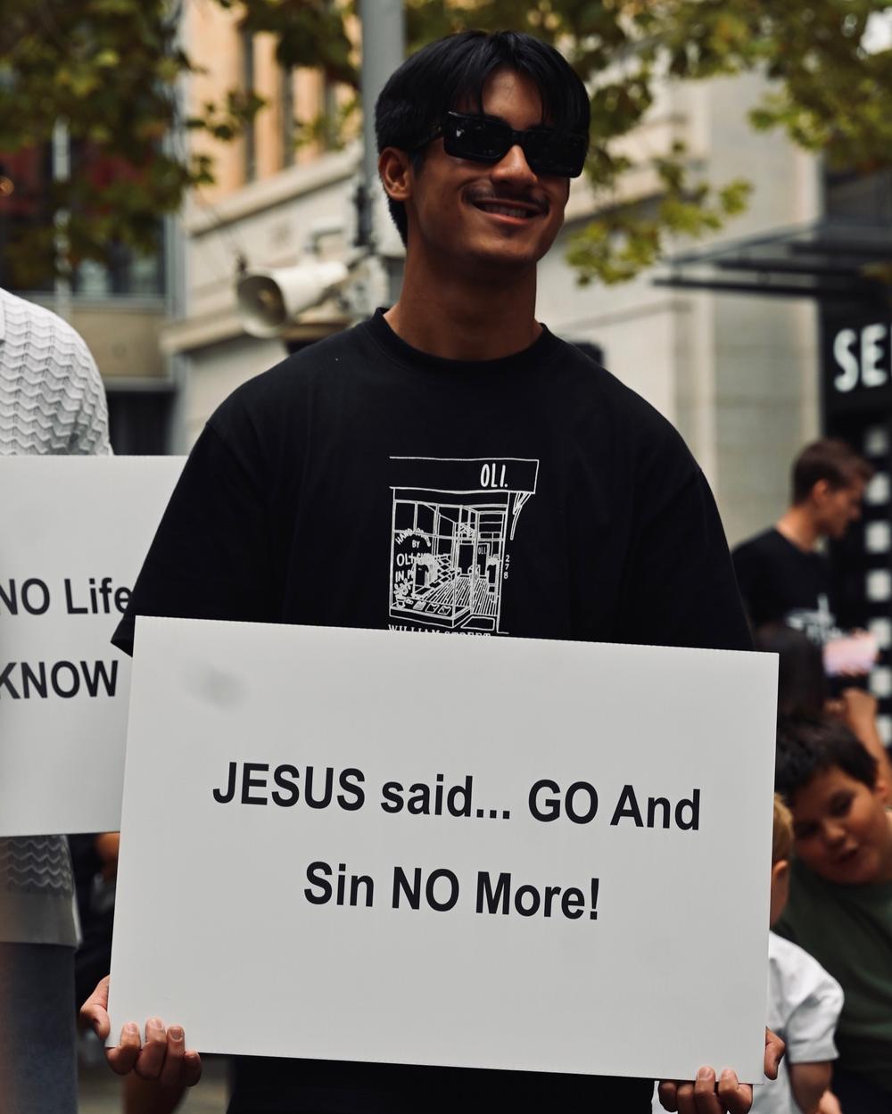 A man holding a sign quoting Jesus